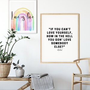 May include: Two framed prints on a white wall. The print on the left features a rainbow with the text "Love is love". The print on the right features a quote by RuPaul: "If you can't love yourself, how in the hell you gon' love somebody else?"