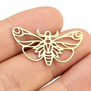 Puede incluir: Encanto de metal dorado en forma de polilla con detalles intrincados. El encanto está recortado y tiene un diseño delicado.