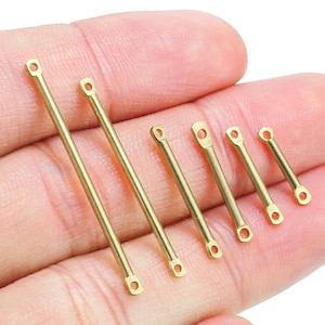 May include: A set of seven gold-coloured metal connector bars with rounded ends. The bars are of varying lengths, with the longest bar being approximately 7.6 cm long.