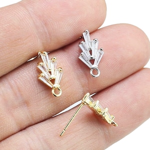 May include: Three gold-tone earring findings with clear crystal accents. The findings are shaped like a fan with a loop at the bottom for attaching to an earring.