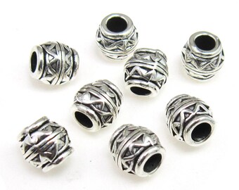 May include: Ten silver-toned metal beads with a geometric design. The beads are oval-shaped and have a hole in the centre.