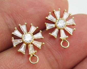 May include: A pair of gold-tone earring charms with a round, clear crystal center surrounded by smaller clear crystals. Each charm has a gold loop for attaching to a chain or earring.
