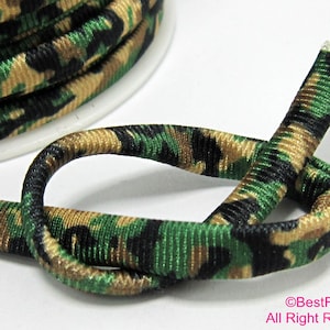 May include: Green, black, and tan camouflage elastic cord. The cord is ribbed and has a stretchy texture.