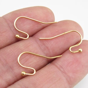 May include: A pair of gold-toned earring hooks with small round balls at the end.