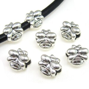 May include: Silver tone metal flower shaped beads for jewelry making. The beads have a detailed design and are perfect for adding a touch of elegance to any project.