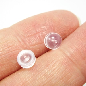 May include: Two clear plastic earring backs with a small hole in the center.