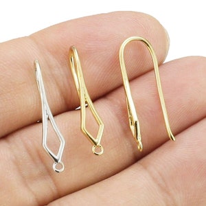 Puede incluir: Tres ganchos para pendientes de oro, dos con una abertura en forma de diamante y uno con una abertura redondeada.