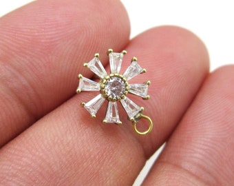 Könnte beinhalten: Goldfarbener Anhänger mit einem klaren Kristall in der Mitte, umgeben von kleineren klaren Kristallen in einem Sternburst-Design. Der Anhänger hat eine Schlaufe unten zum Anbringen an einer Kette.