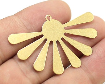 May include: Gold metal charm with a sunburst design. The charm has a hole at the top for attaching to a necklace or bracelet.