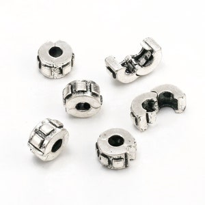 May include: Six silver-toned metal bead spacers with a square pattern. The spacers are designed to be used with charm bracelets.