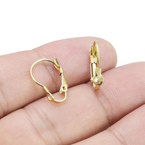 Op de afbeelding: Twee gouden oorclips. De clips zijn gemaakt van metaal en hebben een eenvoudig, elegant ontwerp.
