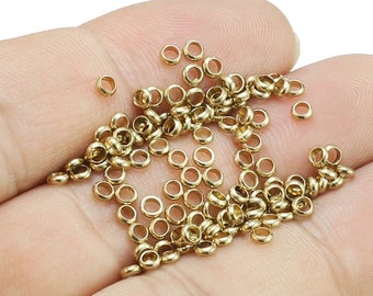 May include: A pile of gold-colored jump rings, also known as split rings, are shown in a hand. These rings are used for jewelry making and crafting.