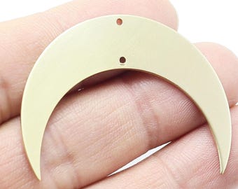 May include: A gold-colored crescent moon charm with two holes for attaching to jewelry or other crafts.