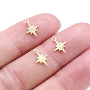 May include: Three gold-toned star charms with a textured surface. The charms have a loop at the top for attaching to jewelry.