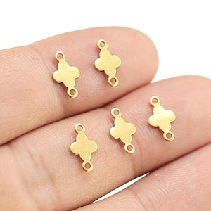 May include: Five gold-toned metal connector charms with a four-leaf clover design. Each charm has two jump rings for attaching to jewelry.