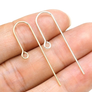 May include: Two metal earring hooks, one gold-toned and one silver-toned, are displayed against a neutral background. The hooks have a simple, curved design with a loop at the top and a straight post at the bottom, perfect for jewelry making.