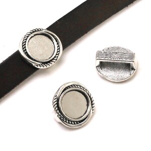 May include: Three round silver-toned metal sliders with a rope-textured border and a flat circular center. One slider is positioned on a dark brown leather strap, while the other two are shown separately, revealing a rectangular loop on the back.