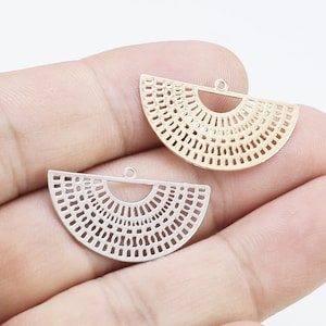 Peut inclure: Deux breloques pendantes en métal en forme de demi-cercle avec un motif découpé décoratif. Le charme à gauche est argenté et le charme à droite est doré.