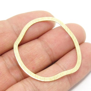 Könnte beinhalten: Ein goldfarbener Metallring mit einer strukturierten, unregelmäßigen Form. Der Ring hat einen Durchmesser von etwa 5 cm.