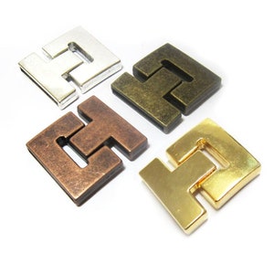 Può includere: Quattro chiusure quadrate in metallo in diverse finiture: argento, ottone, rame e oro. Ogni chiusura ha un design unico con una sezione centrale rialzata.