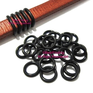 Puede incluir: Primer plano de un montón de juntas tóricas de goma negra. Las juntas tóricas son pequeñas y redondas, y se utilizan para sellar huecos entre objetos.