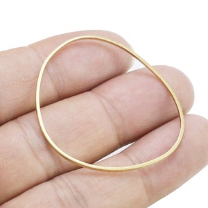May include: A gold-colored metal ring, shown on a hand, is a simple and elegant piece of jewelry.