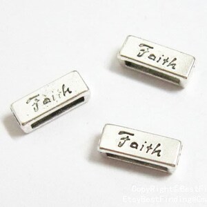 Puede incluir: Tres deslizadores de metal plateado con la palabra "Faith" grabada en cada uno. Los deslizadores son de forma rectangular y tienen un acabado liso y pulido.