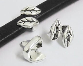 May include: Silver-toned metal leaf-shaped leather cord end caps. Two caps are shown together, and one cap is shown separately.