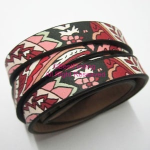 May include: A close-up of a black leather bracelet with a colourful paisley pattern. The bracelet is rolled up and the pattern is visible on all sides.