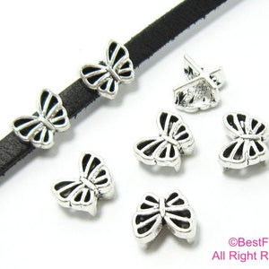 May include: Silver butterfly charms with a black leather cord. The charms are approximately 2.5 cm in size and have a detailed design.