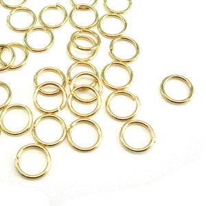 May include: A large quantity of gold jump rings, which are small metal rings used for jewelry making.