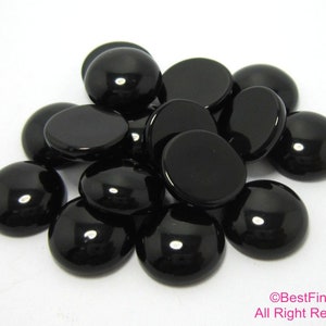 May include: A group of black round cabochon glass gems. The gems are smooth and shiny.