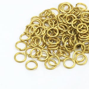 Könnte beinhalten: Ein großer Haufen goldener Sprungringe. Die Ringe sind klein und rund und perfekt zum Schmuckmachen.