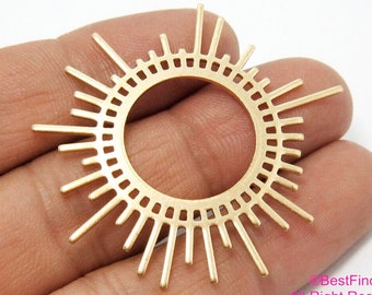 May include: Gold metal sunburst charm with a circular cutout in the center. The charm has a geometric design with a repeating pattern of lines.