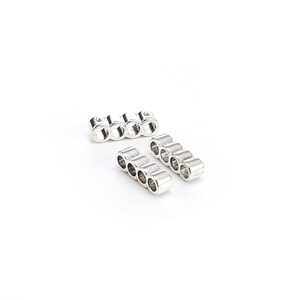 May include: Two silver metal connector pieces for jewelry making. Each piece has five round holes for threading beads or other jewelry components.