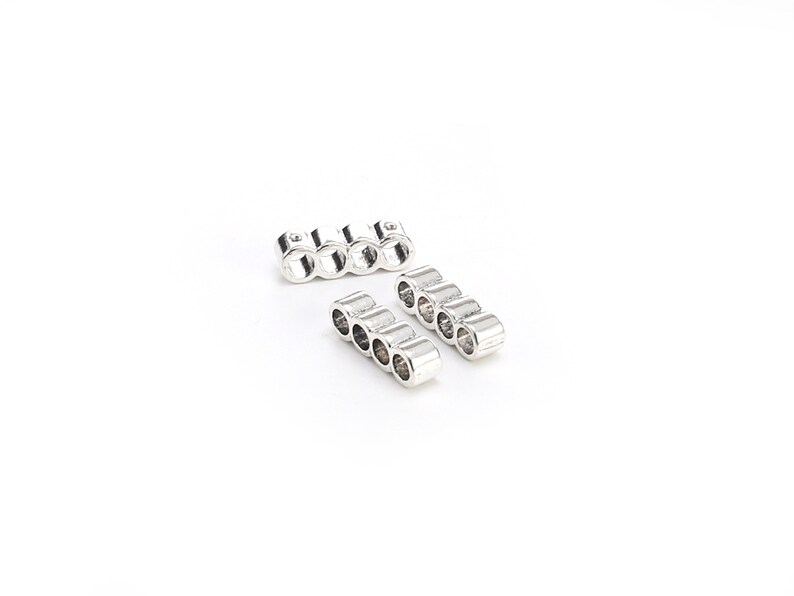 May include: Two silver metal connector pieces for jewelry making. Each piece has five round holes for threading beads or other jewelry components.