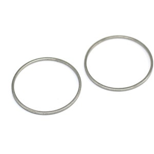 May include: Two silver metal rings, each with a smooth, circular shape. The rings are slightly different in size, with the larger ring on the right and the smaller ring on the left.
