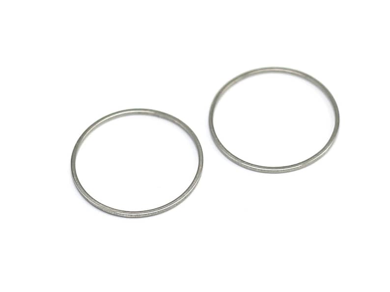 May include: Two silver metal rings, each with a smooth, circular shape. The rings are slightly different in size, with the larger ring on the right and the smaller ring on the left.