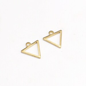May include: Two gold triangle shaped metal charms with a loop at the top for attaching to jewelry or other crafts.
