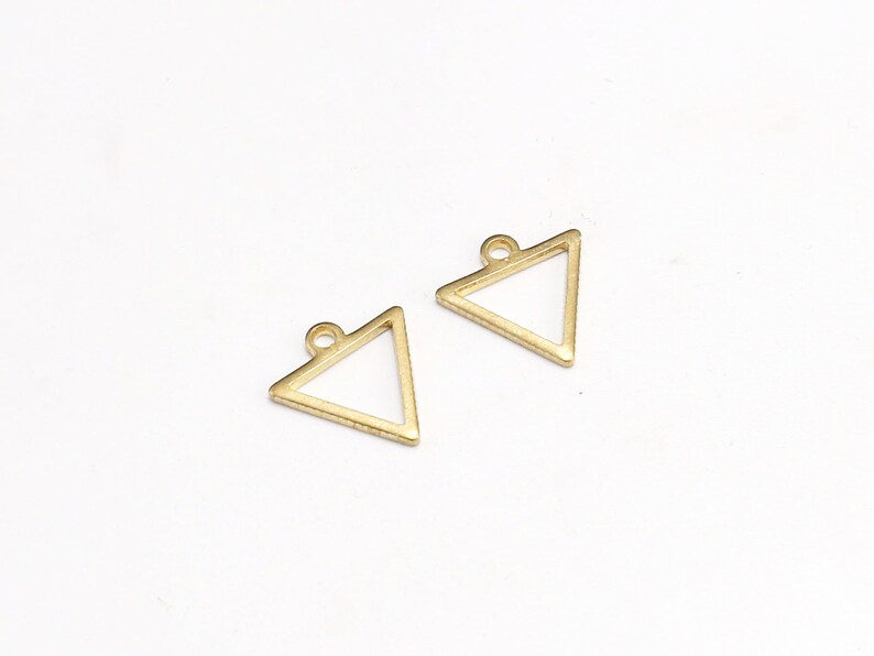 May include: Two gold triangle shaped metal charms with a loop at the top for attaching to jewelry or other crafts.