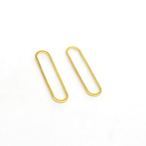 May include: A pair of gold oval-shaped earrings. The earrings are simple and minimalist in design.