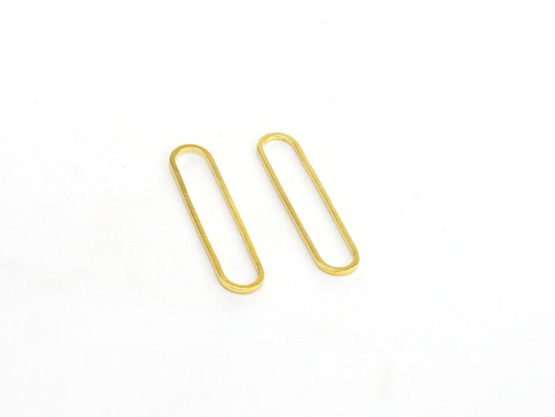 May include: A pair of gold oval-shaped earrings. The earrings are simple and minimalist in design.