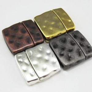 Pode incluir: Quatro fechos magnéticos em diferentes acabamentos: latão antigo, cobre antigo, prata antiga e metal cinza. Cada fecho é retangular com uma textura martelada.