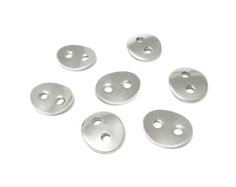 Op de afbeelding: Zeven zilveren metalen knopen met elk twee gaten. De knopen zijn ovaalvormig en hebben een gladde, glanzende afwerking.