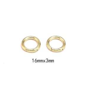 Pode incluir: Dois an&eacute;is redondos dourados com fecho de mola. Cada anel tem uma abertura articulada para fixa&ccedil;&atilde;o. O texto "16mmx3mm" est&aacute; abaixo, indicando o seu tamanho.