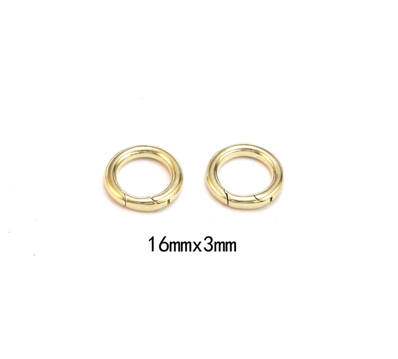 Pode incluir: Dois an&eacute;is redondos dourados com fecho de mola. Cada anel tem uma abertura articulada para fixa&ccedil;&atilde;o. O texto "16mmx3mm" est&aacute; abaixo, indicando o seu tamanho.