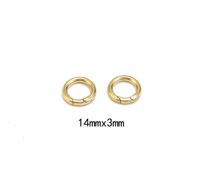 Pode incluir: Duas fivelas circulares douradas com abertura articulada. As fivelas t&ecirc;m 1,4 cm de di&acirc;metro e 3 mm de espessura. Em fundo branco.
