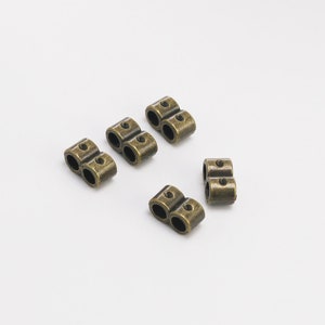 May include: Five antique gold-toned metal double-loop cord ends. These are useful for jewelry making, leather crafting, and other DIY projects.