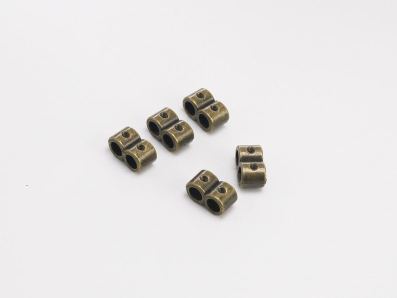 May include: Five antique gold-toned metal double-loop cord ends. These are useful for jewelry making, leather crafting, and other DIY projects.