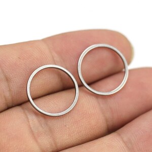 May include: A pair of silver hoop earrings. The earrings are simple and minimalist, with a smooth, polished finish.